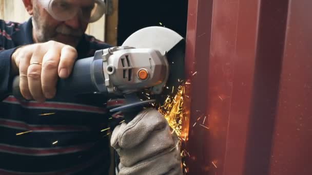 Человек распиливает металлическую конструкцию циркулярной пилой — стоковое видео