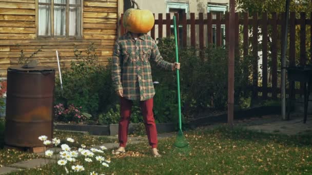 Pumpkinhead person with rake in the garden — Stock Video