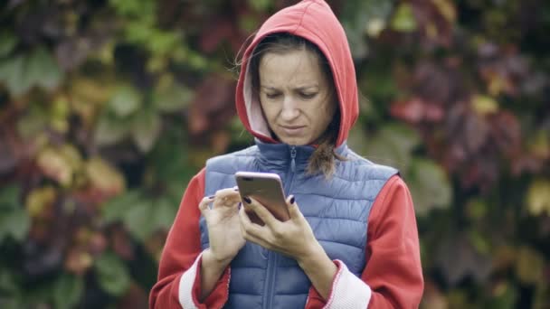 Молодая женщина использует свой мобильный телефон снаружи — стоковое видео