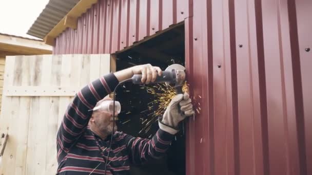 Старший чоловік ріже металеву конструкцію з циркулярною пилкою — стокове відео