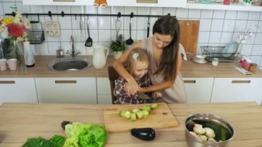 Anne ve kızı mutfakta sebze yemek