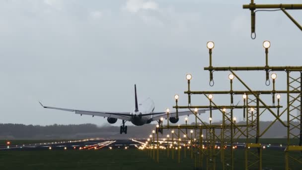 Самолет с двумя двигателями приземляется на освещенную взлетно-посадочную полосу — стоковое видео