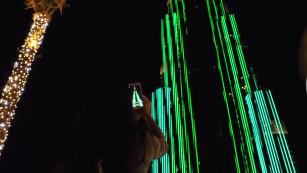 Meisje schieten op haar smartphone de Burj Khalifa toren in de nacht — Stockvideo