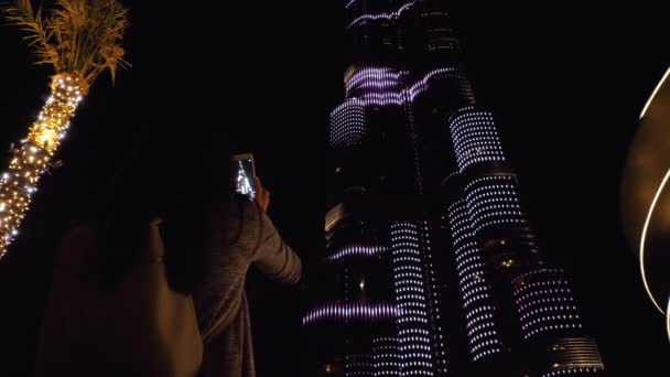 Flicka skjuta på sin smartphone tornet Burj Khalifa på natten — Stockvideo