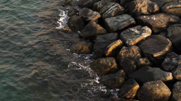 Waterspatten tegen rotsen bij de zonsondergang — Stockvideo