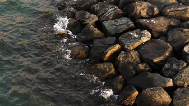 Waterspatten tegen rotsen bij de zonsondergang — Stockvideo