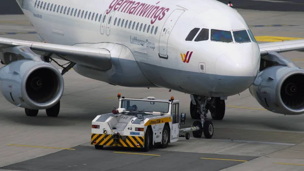 Tracteur de remorquage poussant Airbus A319 à l'aéroport de Düsseldorf — Photo