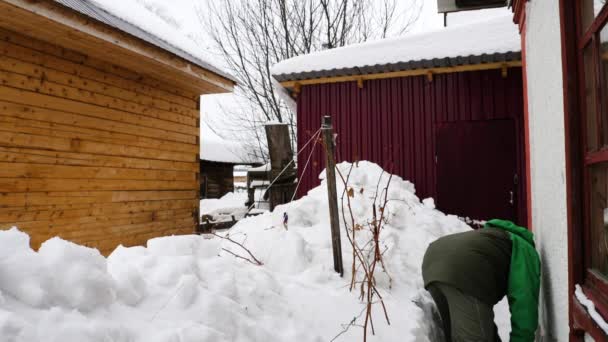 Man städar snö nära huset — Stockvideo