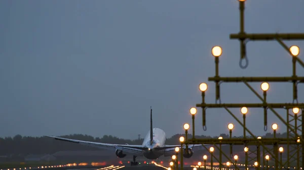 Un avion à fuselage large atterrit sur une piste éclairée — Photo
