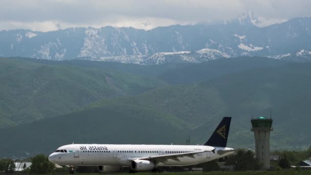Airbus A320 компании "Эйр Астана" разворачивается на взлетно-посадочной полосе против гор — стоковое видео