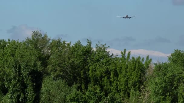 Коммерческий самолет приближается с красивыми горами на заднем плане — стоковое видео