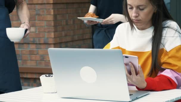 Mujer joven uso de la computadora portátil en la cafetería al aire libre — Vídeos de Stock