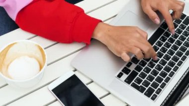 Açık hava kafede dizüstü bilgisayar klavyesi üzerinde yazarak kadın eller.