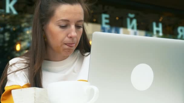Genç kadın açık kafede dizüstü bilgisayar kullanıyor. — Stok video