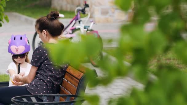 Madre e hija en el banco en el parque — Vídeos de Stock