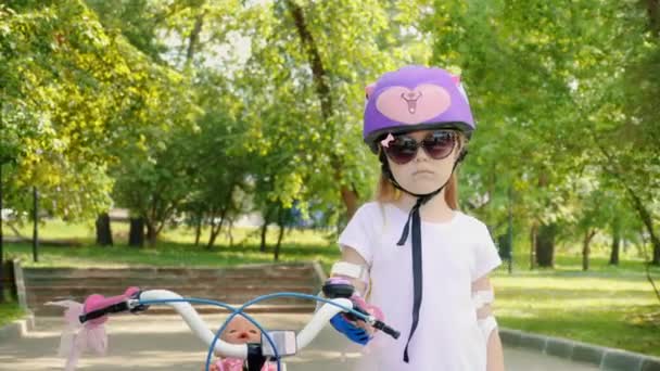 Portret van een klein schattig meisje in een paarse fietshelm — Stockvideo