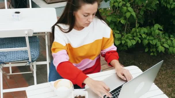 Freelancer dziewczyna pracuje z laptopem w kawiarni na zewnątrz — Wideo stockowe