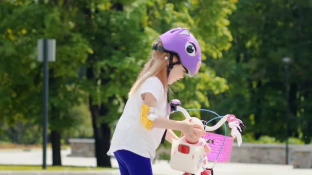 Kleines Mädchen mit Puppe auf Fahrrad — Stockvideo