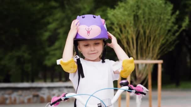 Petite fille mettre le casque de vélo protecteur et rouler à vélo — Video