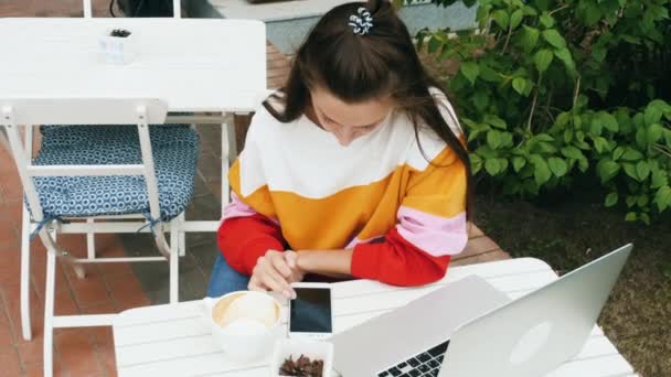 Νεαρή γυναίκα που χρησιμοποιεί το κινητό τηλέφωνο στο καφέ — Αρχείο Βίντεο