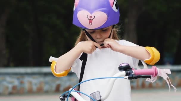 Petite fille mignonne met un casque de vélo de protection — Video