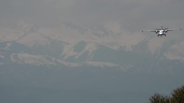 雪に覆われた山々に対して着陸に近づくターボプロップ機 — ストック動画
