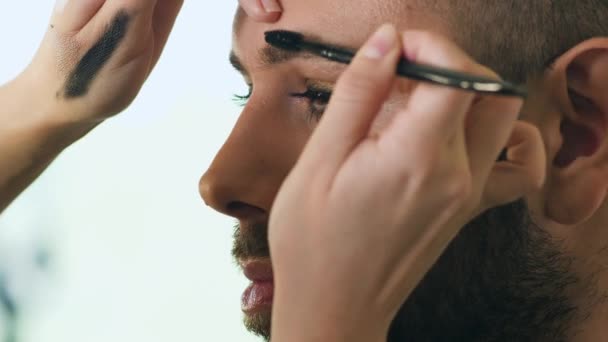 Μακιγιάζ καλλιτέχνης κάνει μακιγιάζ στο πρόσωπο του μουσάτος άνθρωπος — Αρχείο Βίντεο