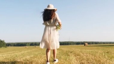 Çayırda çalışan çiçeklerle saman şapkalı kadın