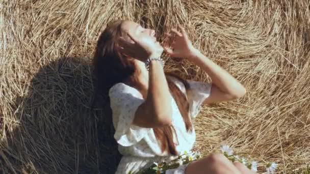 干し草の山に対する花を持つわら帽子の女性 — ストック動画