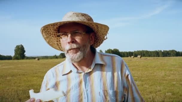 Senior man Eet meloen in de weide — Stockvideo