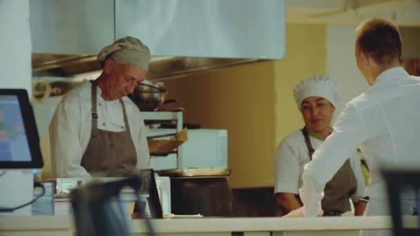 Étterem konyha. Mosolygós szakács és pincér, mely ételeket szolgál fel — Stock videók