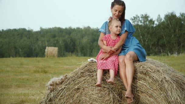 Мать с дочерью сидит на стоге сена — стоковое видео