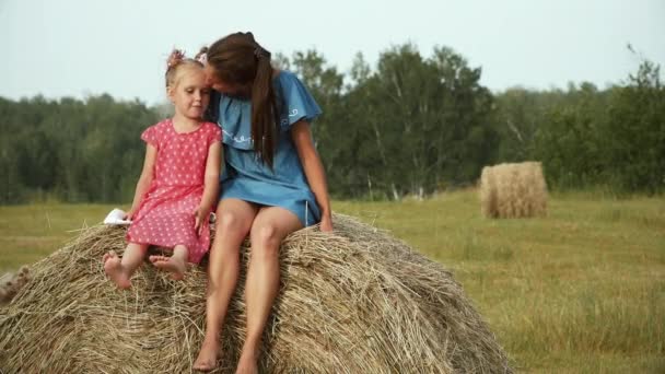 Женщина и пятилетний ребенок сидят на стоге сена — стоковое видео