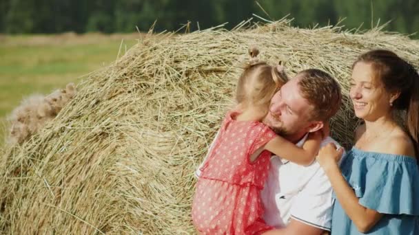 Happy family in the meadow posing against haystack — Stock Video