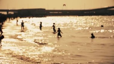 İnsanlar altın saatte rahatlayıp plajda oynarlar.