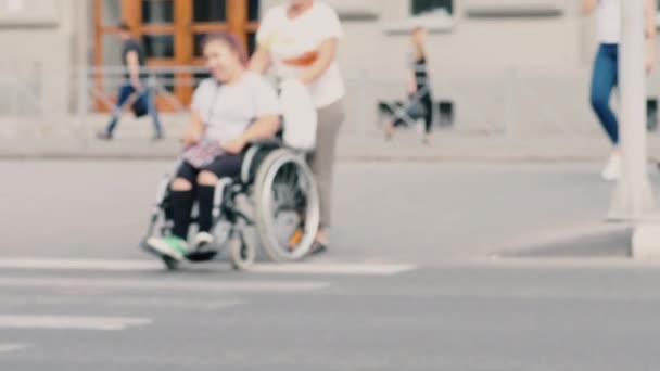 Kvinna transporterar tonåring i rullstol — Stockvideo