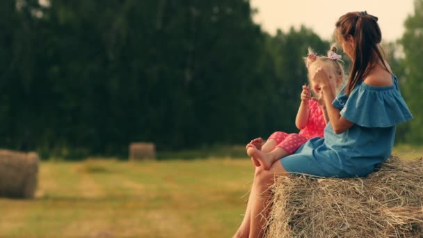 Moeder met daugter op hooiberg bij zonsondergang — Stockvideo