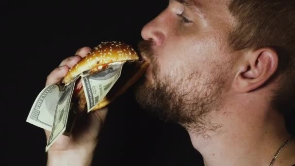 Человек ест бургер с долларами США — стоковое видео