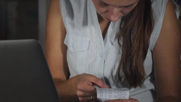 Vrouw kijkt door een cheque terwijl ze een gezinsbudget plant — Stockvideo