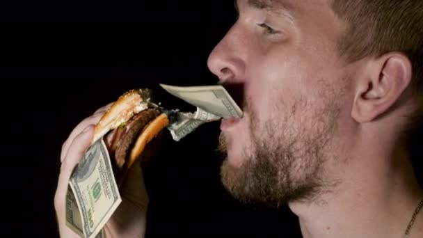 Человек ест гамбургер с долларовыми купюрами внутри — стоковое видео