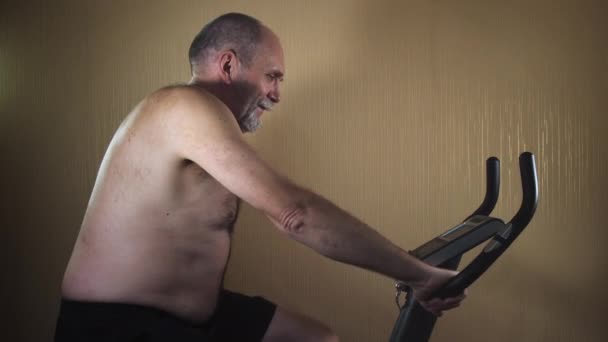 Ο ανώτερος εκπαιδεύεται σε ένα ποδήλατο γυμναστικής. — Αρχείο Βίντεο