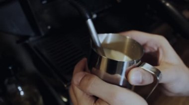 Barista kahve makinesindeki sütü çırpıyor.