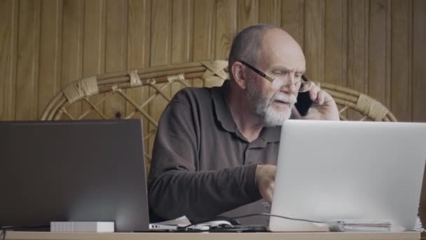 Зрілий бізнесмен працює з ноутбуками — стокове відео