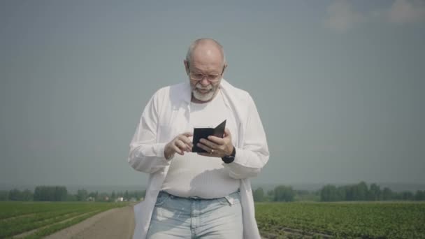 Científico usando el teléfono móvil en el campo — Vídeos de Stock