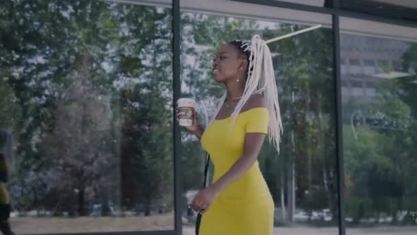 Junge Afrikanerin mit Kaffeebecher unterwegs — Stockvideo