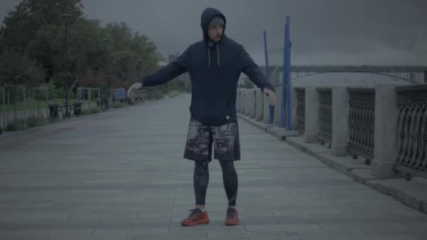 Αθλητικός άνθρωπος στην πόλη Embankment Θερμαίνεται το πρωί — Αρχείο Βίντεο