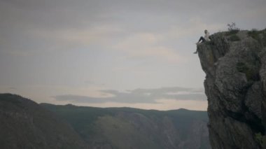 Yürüyüşçü dağın tepesinde oturur.