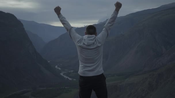 Hombre con las manos extendidas en la cima de una montaña — Vídeo de stock