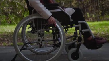 Dışarıda tekerlekli sandalyede bir kadın var.