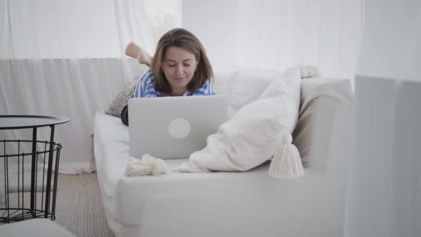 Ung kvinna använder sin bärbara dator hemma — Stockvideo